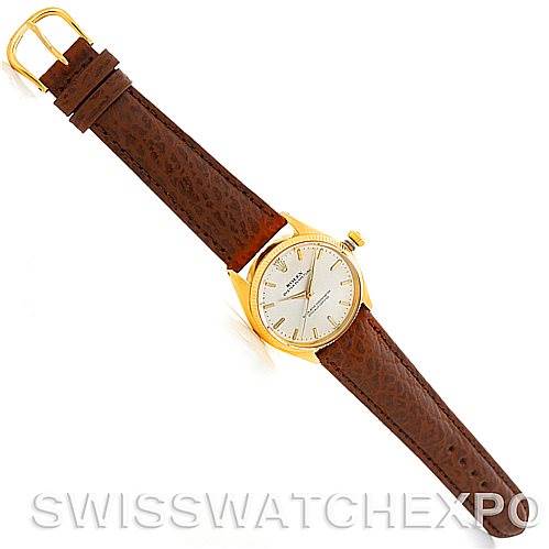 The Rolex President 1005 Men's Yellow Gold Silver Dial 1005 Men's Yellow Gold Silver Dial watch is shown from a top-down angle, displaying its face, case, crown, and brown leather strap.