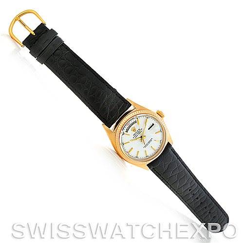 The Rolex President 1803 Men
s Yellow Gold White Dial 1803 Men
s Yellow Gold White Dial watch is shown from a top-down angle, featuring a black leather strap and a gold case with a white dial.