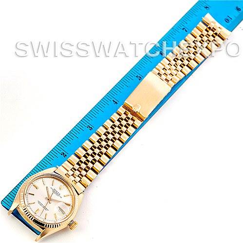 The image shows a Rolex President 1601 Men
s Yellow Gold Silver Dial 1601 Men
s Yellow Gold Silver Dial model watch laid flat next to a blue ruler, displaying the watch face and full bracelet.