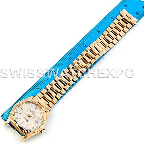 The image shows a top-down view of a Rolex President 16018 Men
s Yellow Gold Silver Dial 16018 Men
s Yellow Gold Silver Dial model watch, including its face, bezel, crown, and full bracelet placed beside a blue ruler.