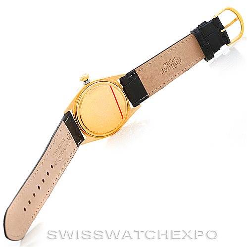 This image shows the back side of a Rolex President 1803 Men
s Yellow Gold Silver Dial 1803 Men
s Yellow Gold Silver Dial model watch lying flat, highlighting its leather strap and gold case.