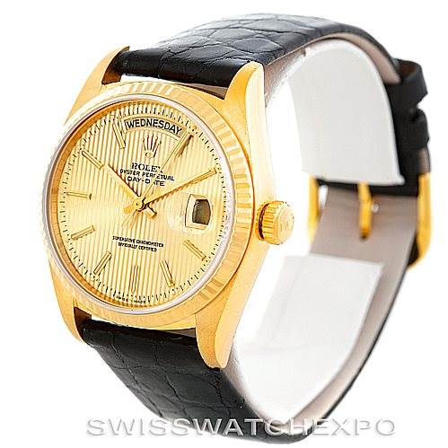 This image showcases a Rolex President 18038 Men
s Yellow Gold Champagne Dial 18038 Men
s Yellow Gold Champagne Dial model watch with a gold case, day-date display, and a black leather strap, viewed at a slight angle.