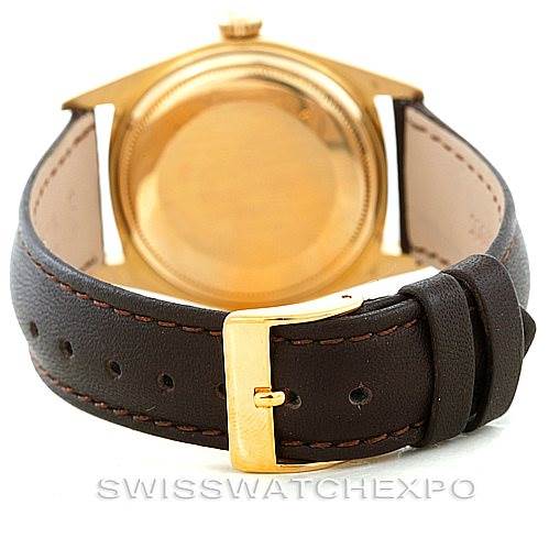 The image shows the back of the gold Rolex President 1601 Men
s Yellow Gold Champagne Dial 1601 Men
s Yellow Gold Champagne Dial watch case and part of the brown leather strap with its buckle.