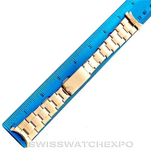 This image shows a close-up view of a gold bracelet for a Rolex President Men's  Men's  model watch, alongside a blue ruler for scale.
