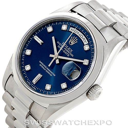 The image shows a close-up view of the Rolex President 18206 Men's Platinum Blue Dial 18206 Men's Platinum Blue Dial watch, featuring its blue dial, diamond hour markers, day/date functions, and metal bracelet.
