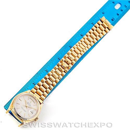 The image shows a Rolex President 18038 Men
s Yellow Gold Silver Dial 18038 Men
s Yellow Gold Silver Dial watch laid flat alongside a blue ruler.