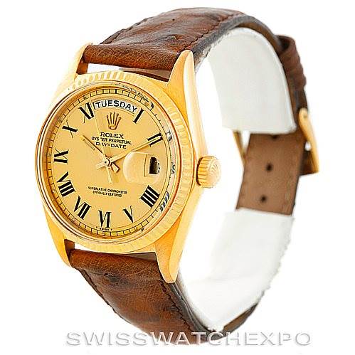 The image shows a gold Rolex President 1803 Men
s Yellow Gold Champagne Dial 1803 Men
s Yellow Gold Champagne Dial model watch with a brown leather strap, featuring a day-date display and Roman numerals.