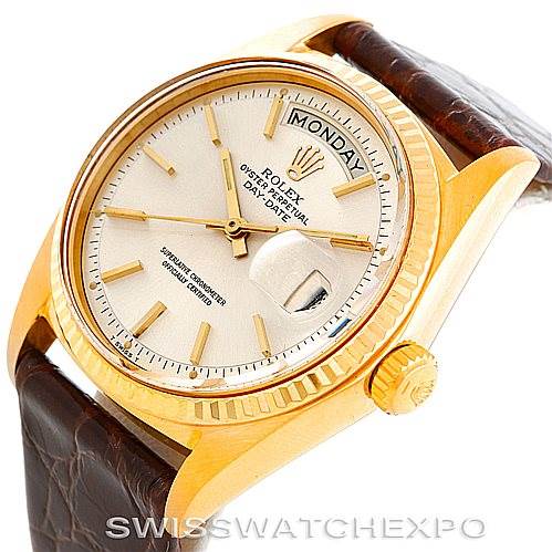 This image shows a Rolex President 1807 Men
s Yellow Gold Silver Dial 1807 Men
s Yellow Gold Silver Dial model watch from a slightly tilted angle, highlighting its gold case, crown, leather strap, and day-date display.