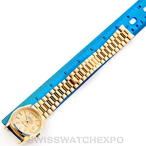 This image shows a top view of a Rolex President 18238 Men
s Yellow Gold Champagne Dial 18238 Men
s Yellow Gold Champagne Dial model watch, highlighting its gold bracelet and face against a blue ruler for scale.