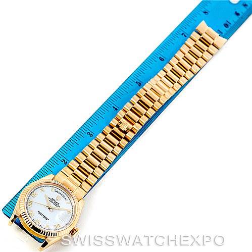 The Rolex President 118238 Men's Yellow Gold White Dial 118238 Men's Yellow Gold White Dial model watch is shown from an overhead angle with a gold bracelet beside a ruler for scale.