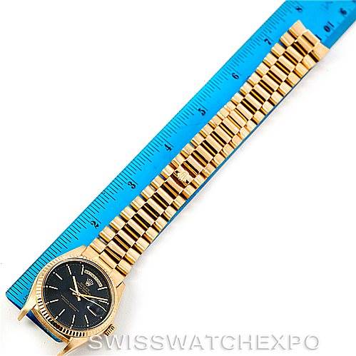 The image shows a Rolex President 1803 Men's Yellow Gold Black Dial 1803 Men's Yellow Gold Black Dial model watch placed alongside a blue measuring ruler, focusing on its face and bracelet.