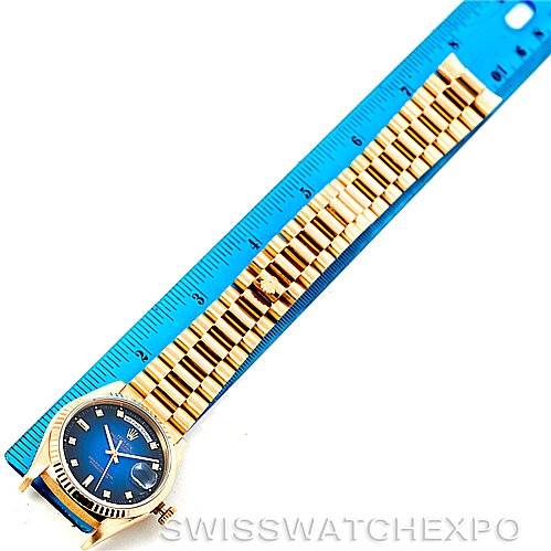 The image shows a Rolex President 18238 Men's Yellow Gold Blue Dial 18238 Men's Yellow Gold Blue Dial model watch with a blue dial and gold bracelet laid next to a blue ruler for measurement.