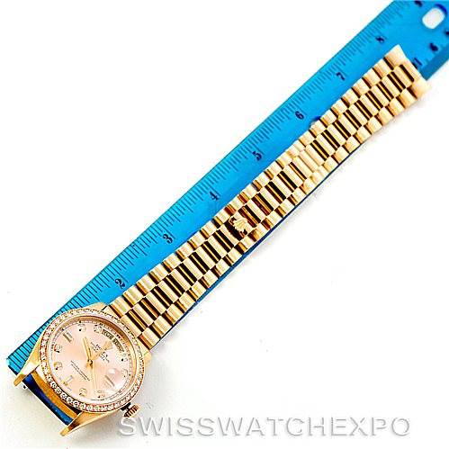 The image shows a Rolex President 18238 Men
s Yellow Gold Champagne Dial 18238 Men
s Yellow Gold Champagne Dial watch face-up with its bracelet aligned next to a blue ruler for measurement.