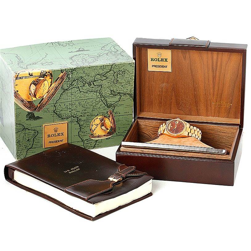 The Rolex President 18038 Men
s Yellow Gold Brown Dial 18038 Men
s Yellow Gold Brown Dial model watch is displayed in its wooden box along with packaging and an accompanying leather-bound booklet.