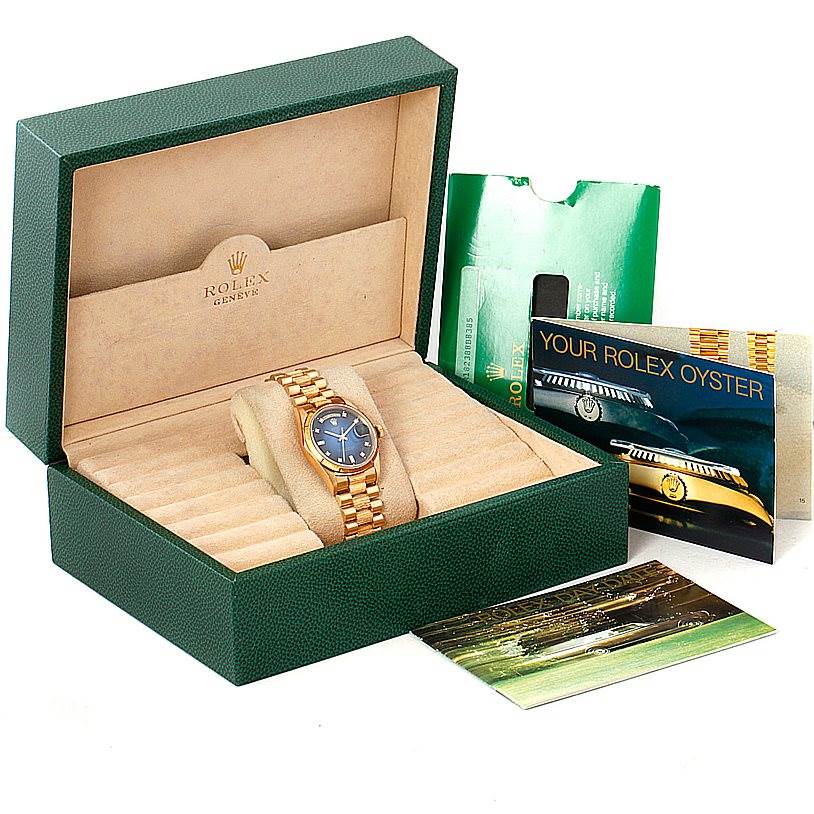 The image shows a Rolex President 18248 Men's Yellow Gold Blue Dial 18248 Men's Yellow Gold Blue Dial model watch in its green box along with booklets and documents.