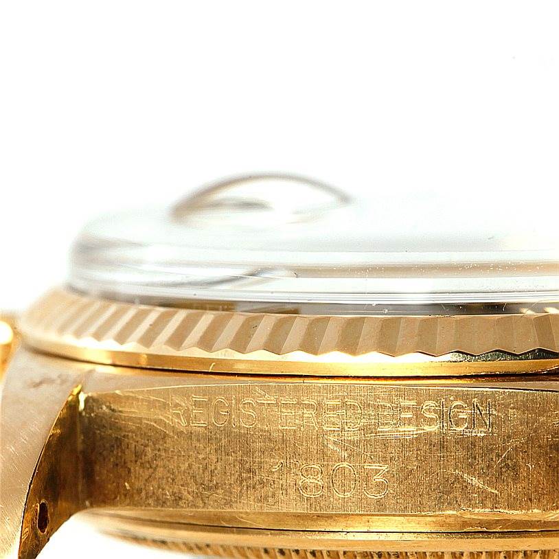 This close-up side view of a Rolex President 1803 Men's Yellow Gold Brown Dial 1803 Men's Yellow Gold Brown Dial model shows the watch's bezel, crystal, and part of the case with the engraved design.