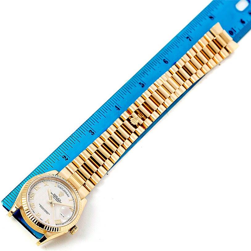 The image shows a Rolex President 118238 Men's Yellow Gold Beige Dial 118238 Men's Yellow Gold Beige Dial model watch with a gold band and a white dial, positioned next to a blue ruler for scale.