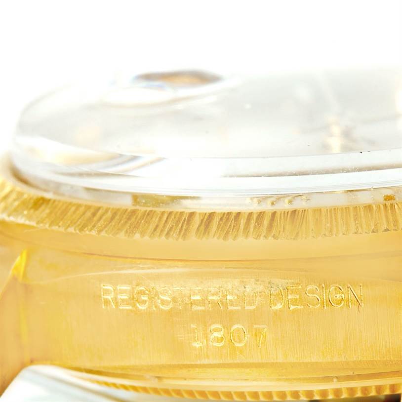 This close-up angle of a Rolex President 1807 Men
s Yellow Gold Silver Dial 1807 Men
s Yellow Gold Silver Dial model watch shows the side of the case with the inscription "REGISTERED DESIGN 1807."