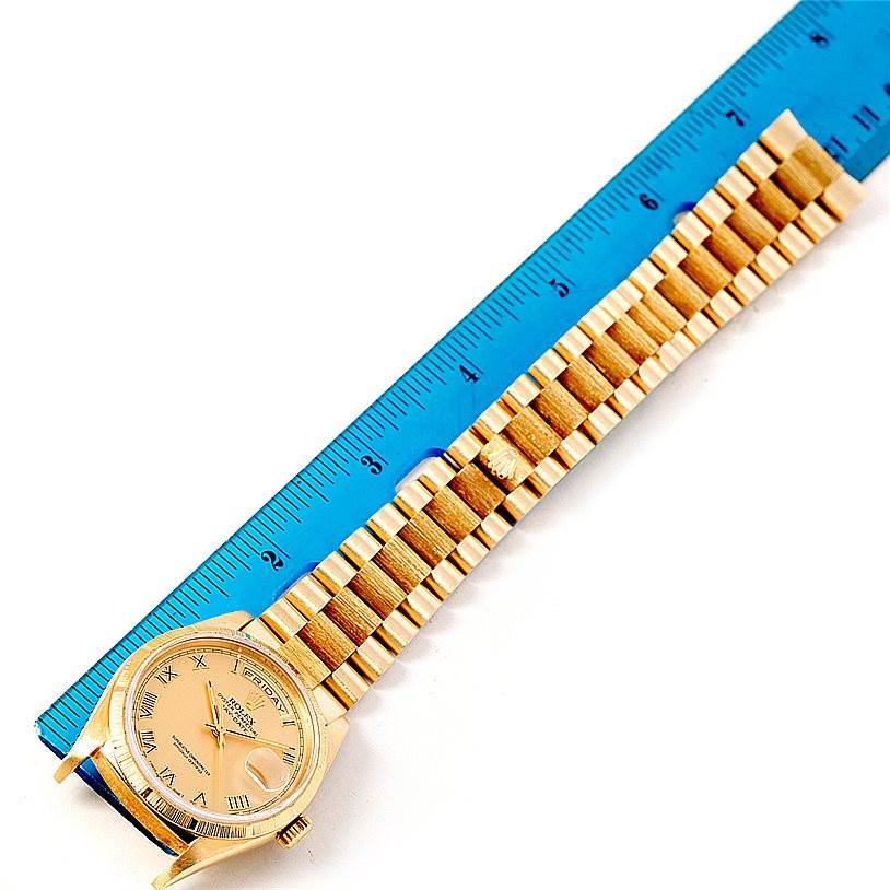 The image shows a Rolex President 18248 Men
s Yellow Gold Champagne Dial 18248 Men
s Yellow Gold Champagne Dial model watch laid next to a blue ruler, displaying the dial and bracelet.