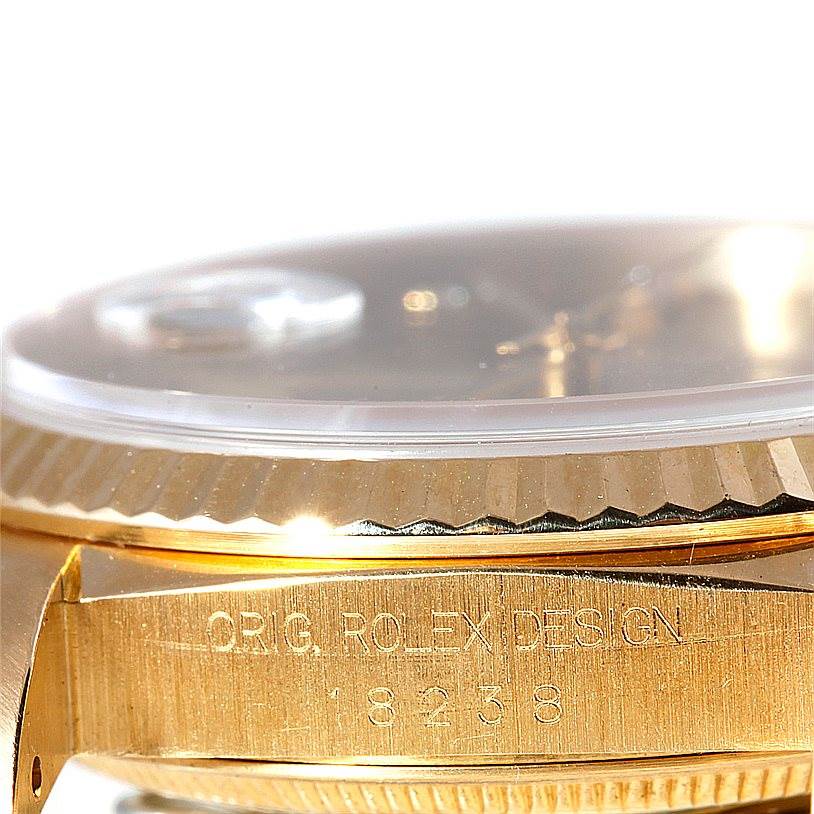 This close-up image of a Rolex President 18238 Men
s Yellow Gold Champagne Dial 18238 Men
s Yellow Gold Champagne Dial model shows the case side with engraved text and part of the fluted bezel.