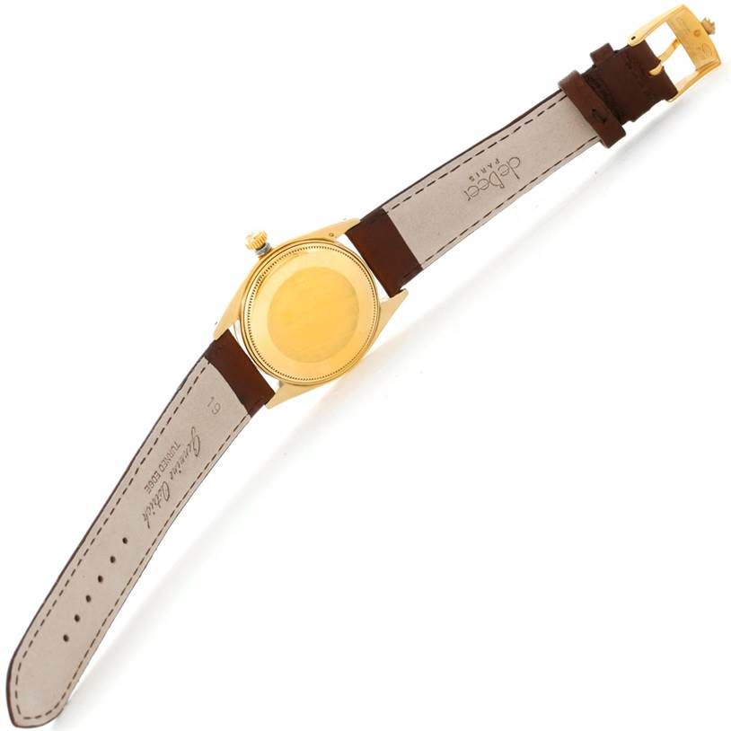 The image shows the back of a Rolex President 1500 Men
s Yellow Gold Champagne Dial 1500 Men
s Yellow Gold Champagne Dial model watch with a brown leather strap and gold case.