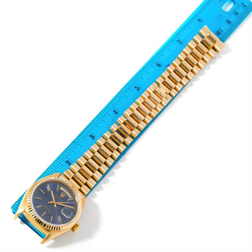 The image shows a Rolex President 18038 Men's Yellow Gold Blue Dial 18038 Men's Yellow Gold Blue Dial model watch laid flat with a blue ruler next to its gold bracelet.