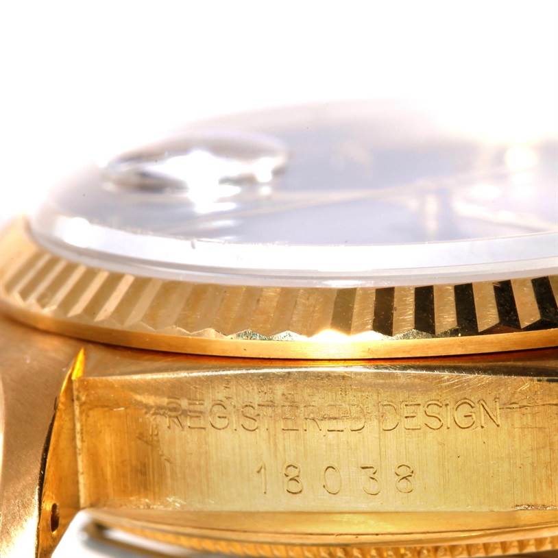 This image shows an angled close-up of the bezel and side of the Rolex President 18038 Men's Yellow Gold Blue Dial 18038 Men's Yellow Gold Blue Dial model watch, displaying its registered design and model number.