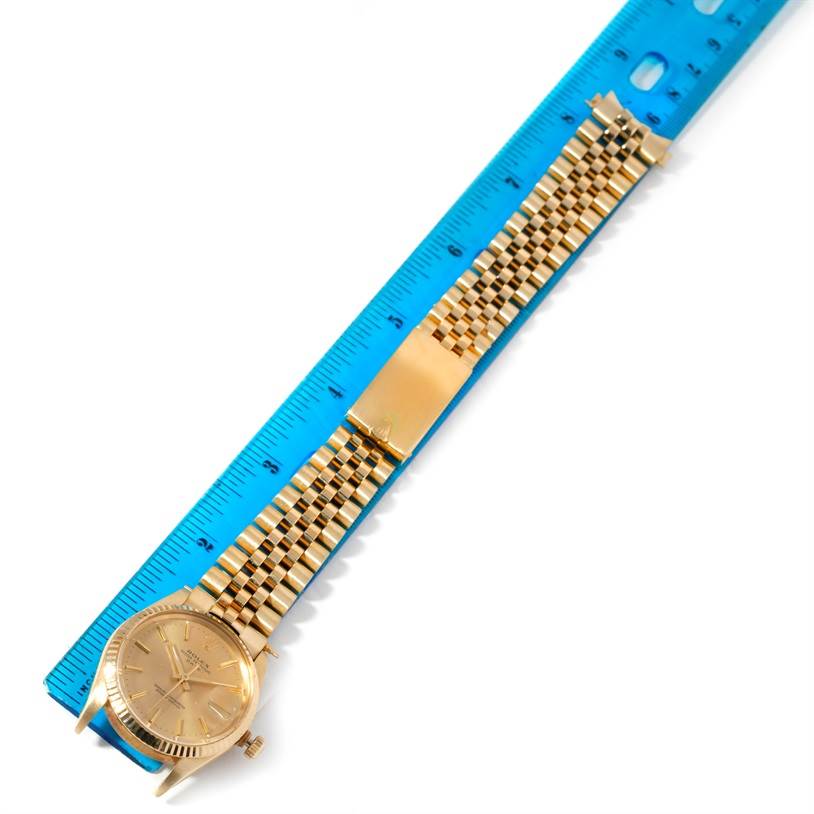 The Rolex President 15037 Men
s Yellow Gold Champagne Dial 15037 Men
s Yellow Gold Champagne Dial model watch is shown flat with a blue ruler beside it, displaying its gold wristband and face.