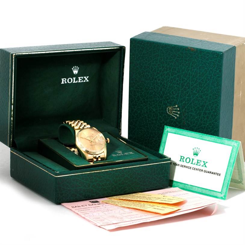 The image shows a Rolex President 15037 Men
s Yellow Gold Champagne Dial 15037 Men
s Yellow Gold Champagne Dial model watch at an angle inside its opened box, along with guarantee paperwork and outer packaging.