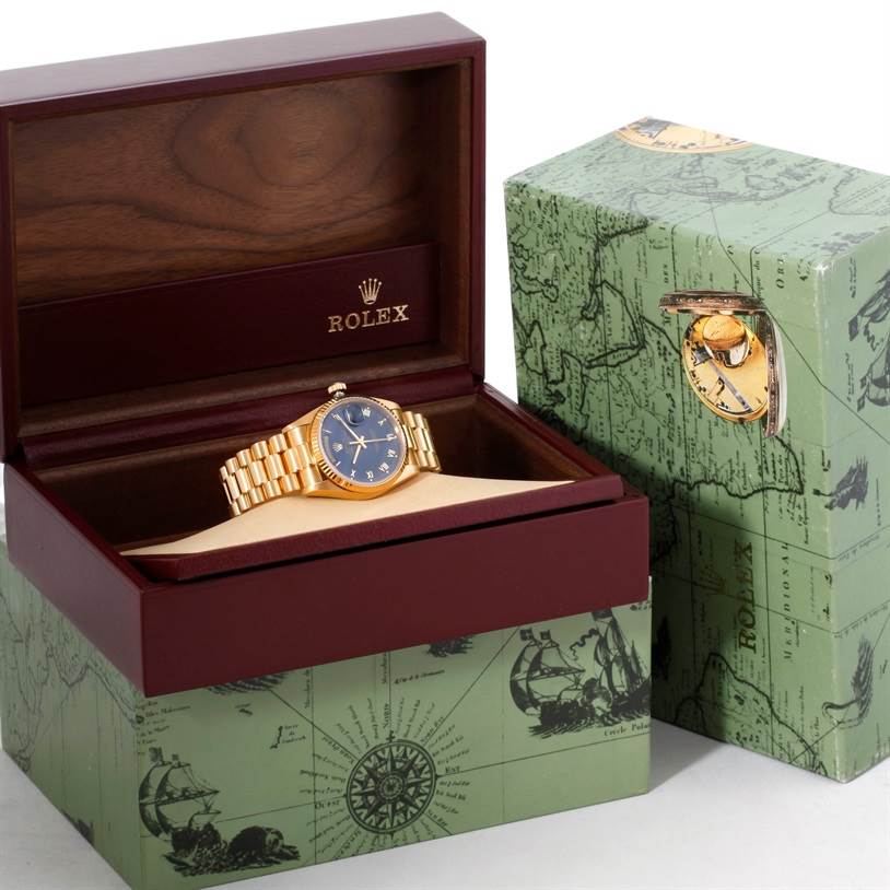 The Rolex President 18038 Men's Yellow Gold Blue Dial 18038 Men's Yellow Gold Blue Dial watch is displayed at an angle inside its open wooden box, accompanied by its outer decorative box.