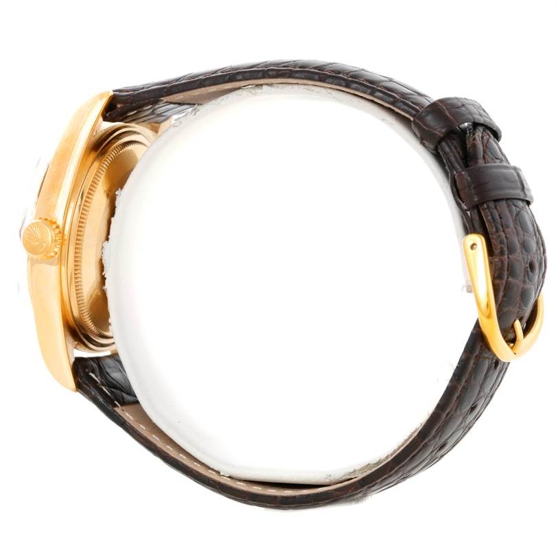 This side view of the Rolex President 1803 Men's Yellow Gold Grey Dial 1803 Men's Yellow Gold Grey Dial model watch showcases its crown, bezel, case, and leather strap with a clasp.