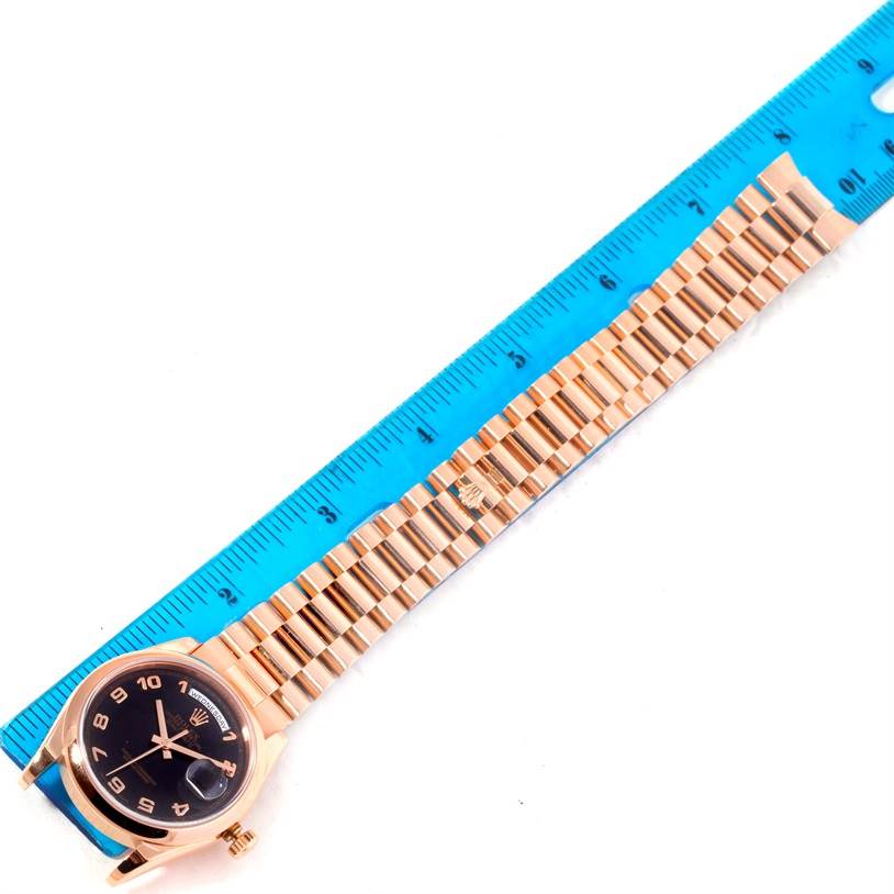 The image shows a Rolex President 118205 Men's Rose Gold Black Dial 118205 Men's Rose Gold Black Dial model watch laid flat next to a ruler, displaying its face and bracelet.