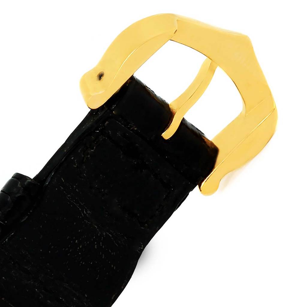 This image shows a close-up of the black leather strap and gold buckle of the Trinity model by Cartier.