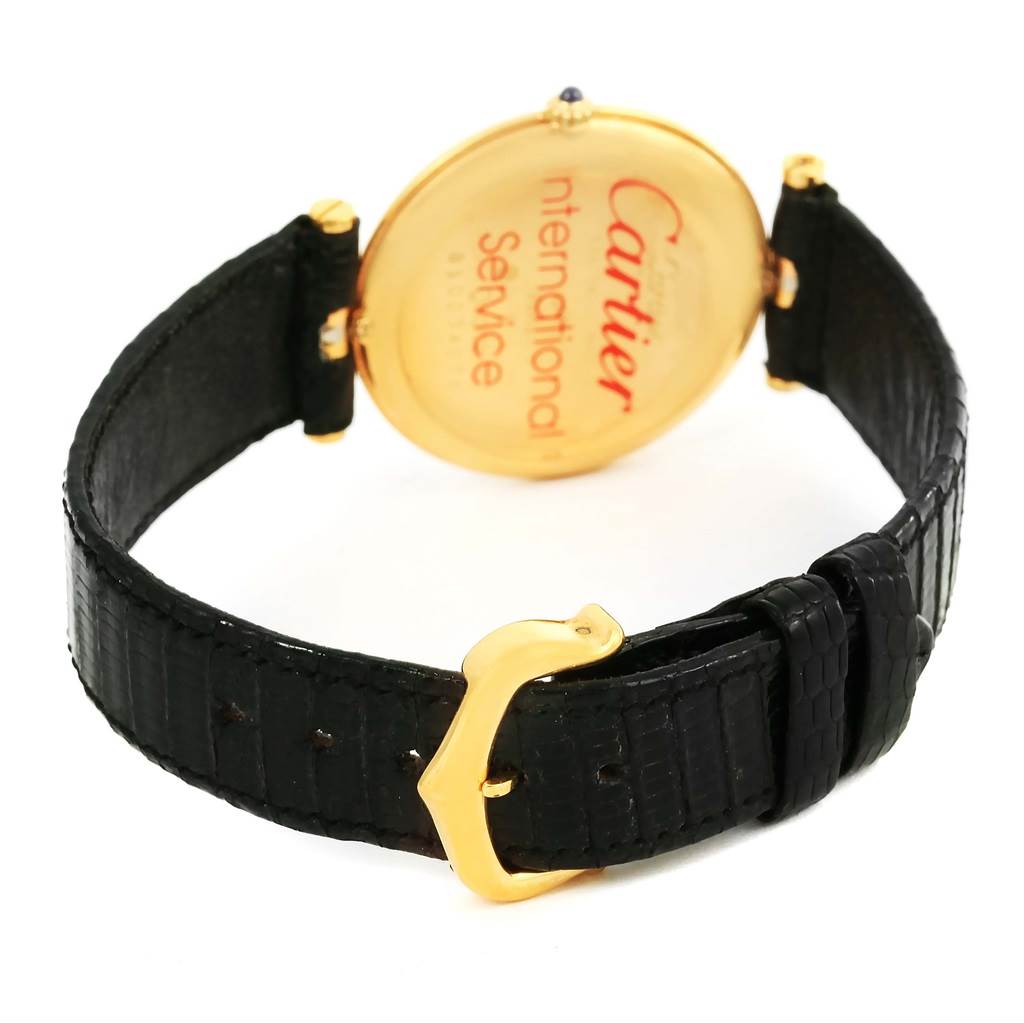 The image shows the back of the Trinity model by Cartier and its black leather strap with a gold buckle.