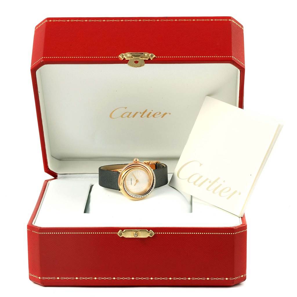 The Cartier Trinity WG200151 Women's Yellow Gold Beige Dial WG200151 Women's Yellow Gold Beige Dial model watch is shown in an open display case with a booklet beside it.