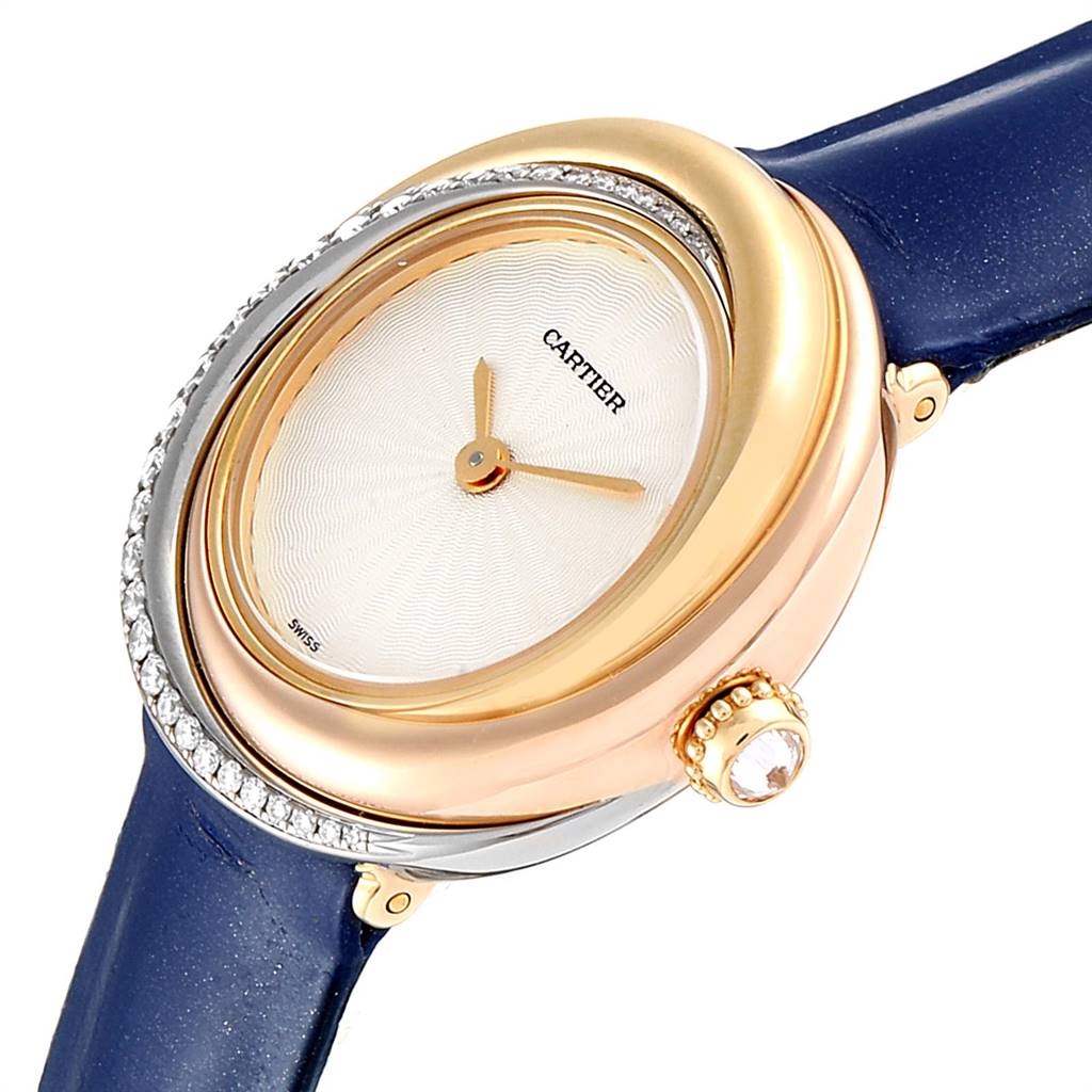 The Cartier Trinity WG200151 Women's Yellow Gold Beige Dial WG200151 Women's Yellow Gold Beige Dial watch is shown at an angle, highlighting the dial, bezel, and part of the blue strap.