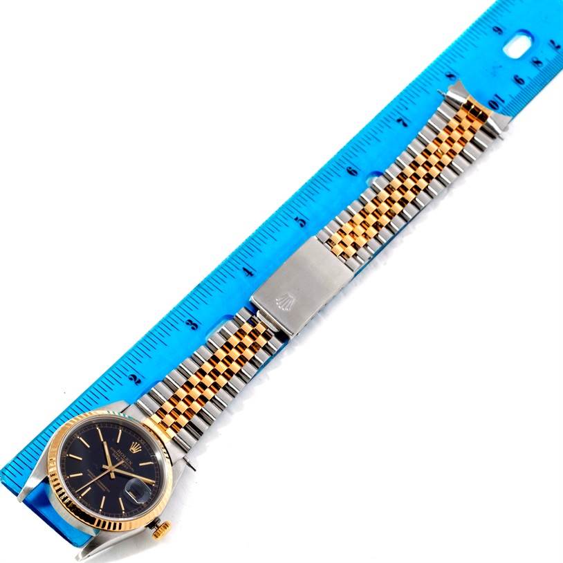 The Rolex Datejust 16233 Men's Steel and Gold (two tone) Black Dial 16233 Men's Steel and Gold (two tone) Black Dial watch is shown from a top-down angle, featuring the face, bezel, and the bracelet fully extended against a ruler.