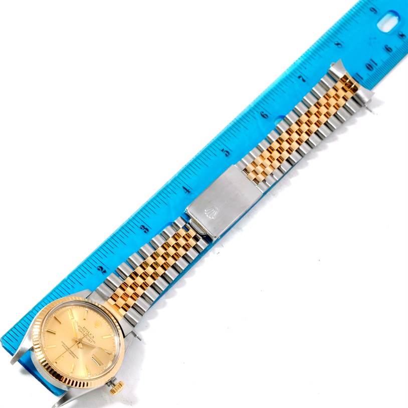 The Rolex Datejust 16013 Men's Stainless Steel Champagne Dial 16013 Men's Stainless Steel Champagne Dial watch is shown in a top-down view, laid out alongside a ruler, highlighting the face and bracelet.