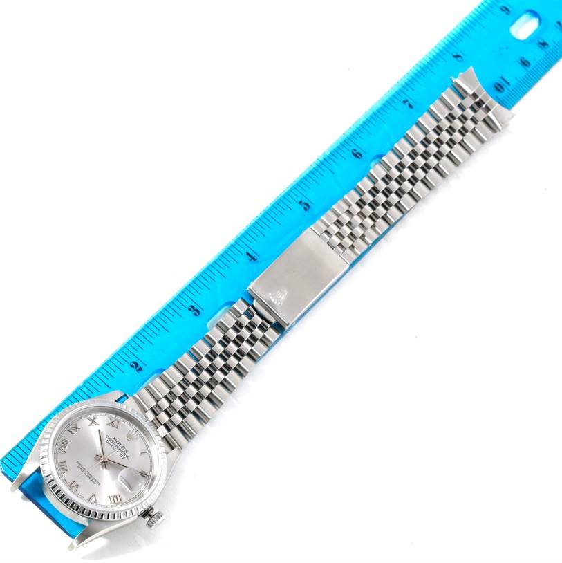 This image shows the Rolex Datejust 16220 Men's Stainless Steel Silver Dial 16220 Men's Stainless Steel Silver Dial watch laid flat next to a blue ruler, highlighting the watch face and the full length of the bracelet.