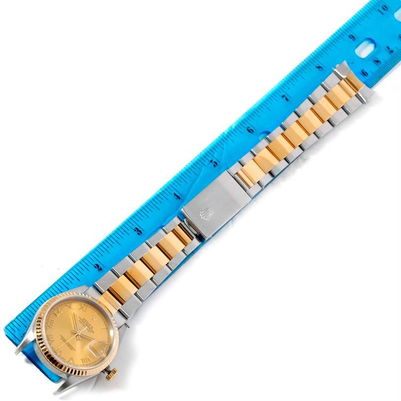 The Rolex Datejust 16233 Men's Steel and Gold (two tone) Champagne Dial 16233 Men's Steel and Gold (two tone) Champagne Dial watch is shown from an overhead angle, displaying its face, bracelet, and clasp, alongside a ruler for scale.