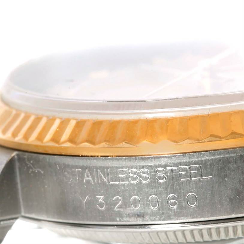 The image shows a close-up of the side view of a Rolex Datejust 16233 Men's Steel and Gold (two tone) Champagne Dial 16233 Men's Steel and Gold (two tone) Champagne Dial watch, highlighting the bezel and part of the casing with engraved text.