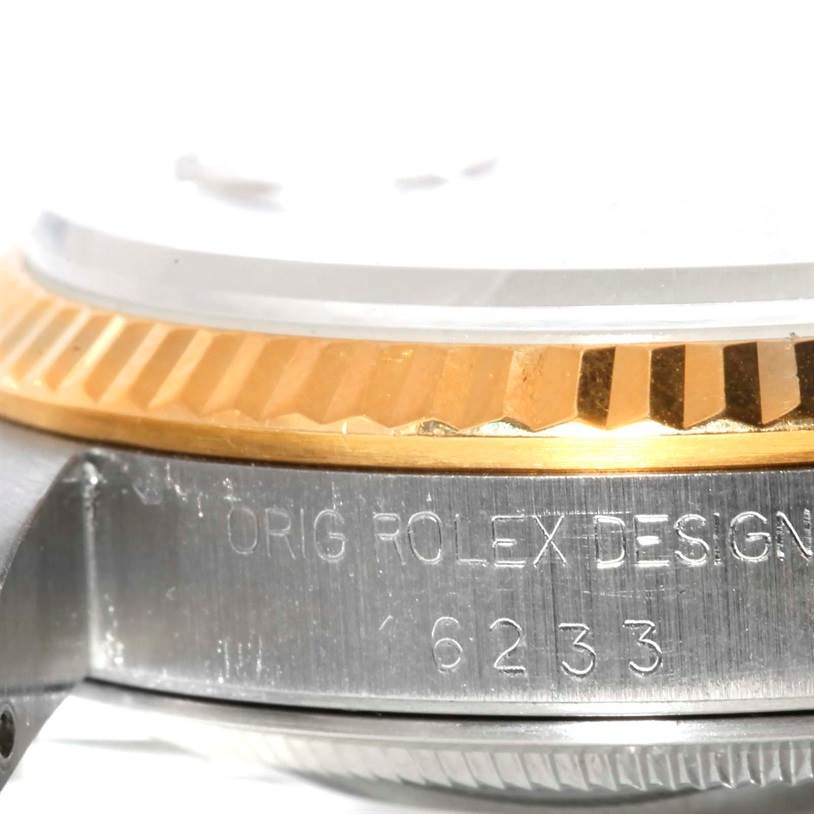 The close-up image shows the side of a Rolex Datejust 16233 Men's Steel and Gold (two tone) Champagne Dial 16233 Men's Steel and Gold (two tone) Champagne Dial watch, highlighting its engraved case and fluted bezel.