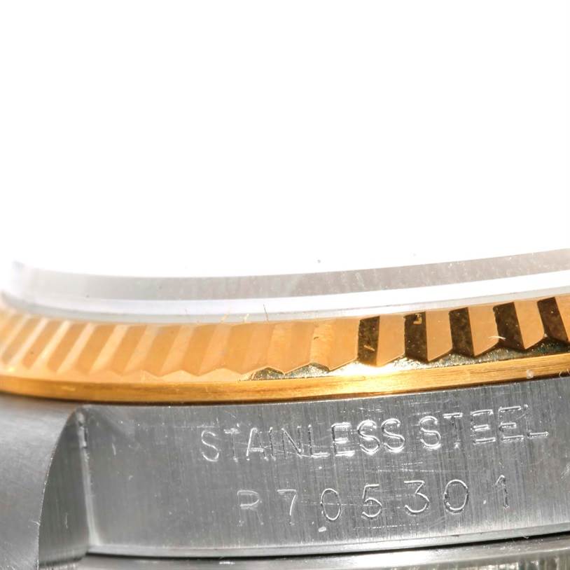 This close-up image of the Rolex Datejust 16233 Men's Steel and Gold (two tone) Champagne Dial 16233 Men's Steel and Gold (two tone) Champagne Dial watch shows the stainless steel and gold fluted bezel and part of the case with engraved text.