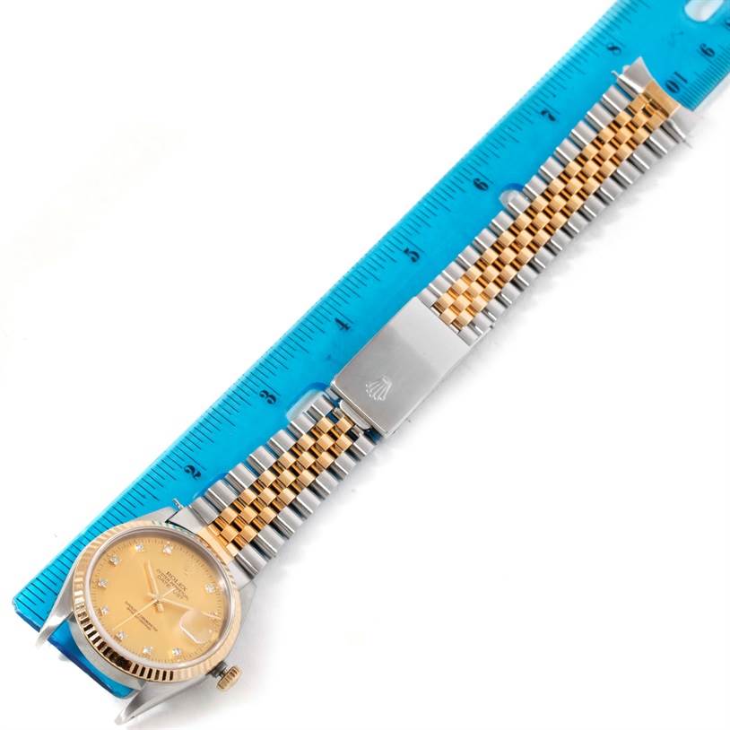 This image shows a Rolex Datejust 16233 Men's Steel and Gold (two tone) Champagne Dial 16233 Men's Steel and Gold (two tone) Champagne Dial watch laid flat with its face and two-tone bracelet displayed, alongside a blue ruler for scale.