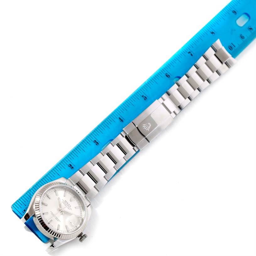 The image shows a Rolex Datejust 116234 Men's Stainless Steel Silver Dial 116234 Men's Stainless Steel Silver Dial watch laid flat with a metal bracelet next to a blue ruler for size comparison.