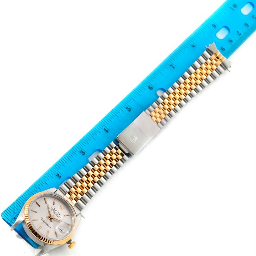 The Rolex Datejust 16233 Men
s Steel and Gold (two tone) Silver Dial 16233 Men
s Steel and Gold (two tone) Silver Dial watch is shown from a top-down angle with a blue ruler for measurement.