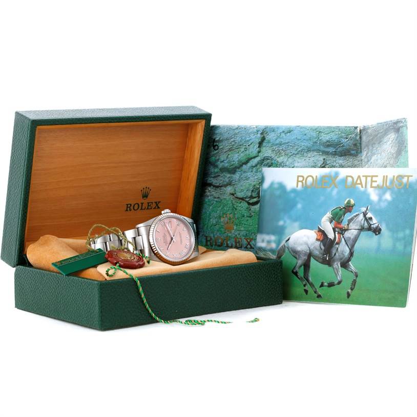 The image shows a Rolex Datejust 16234 Men
s Stainless Steel Pink Dial 16234 Men
s Stainless Steel Pink Dial watch placed in an open box, accompanied by a booklet and accessories, viewed from the front.