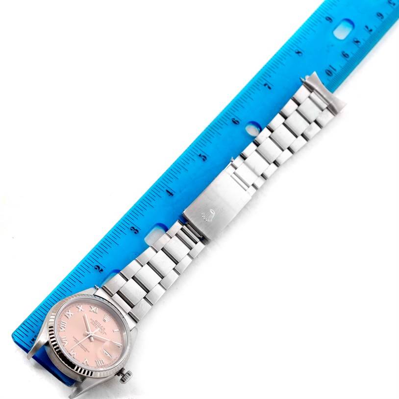 The image shows a Rolex Datejust 16234 Men
s Stainless Steel Pink Dial 16234 Men
s Stainless Steel Pink Dial watch laid flat next to a blue ruler, focusing on the band and clasp.