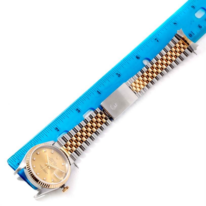 This image shows the Rolex Datejust 16233 Men's Steel and Gold (two tone) Champagne Dial 16233 Men's Steel and Gold (two tone) Champagne Dial watch face and band, measured with a blue ruler, taken from an angled top view.