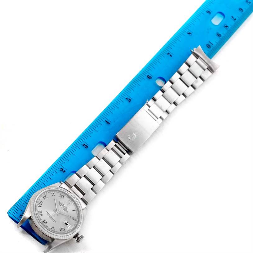 The Rolex Datejust 16234 Men's Stainless Steel Silver Dial 16234 Men's Stainless Steel Silver Dial watch is displayed horizontally with the full bracelet and face visible, measured next to a blue ruler.